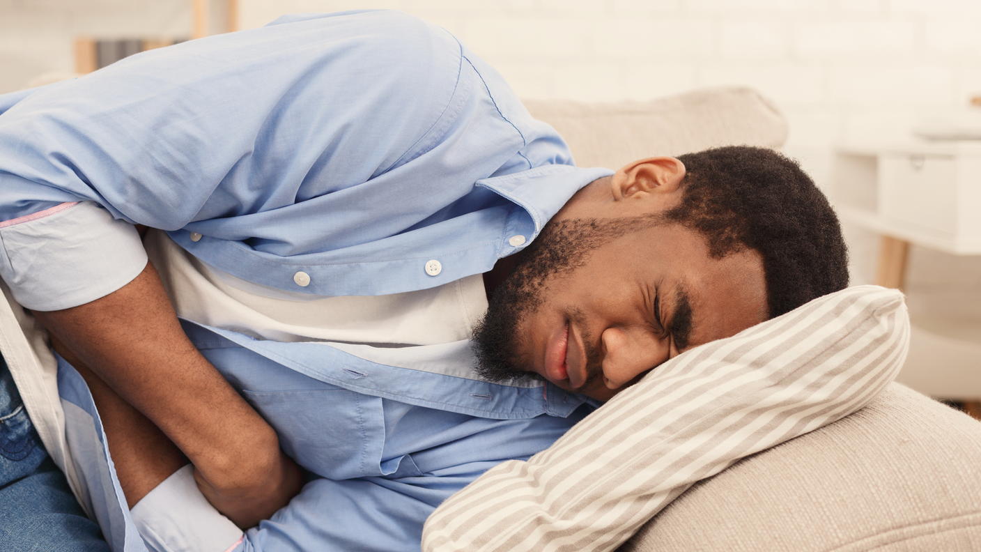 Man lying in bed with a stomach ache